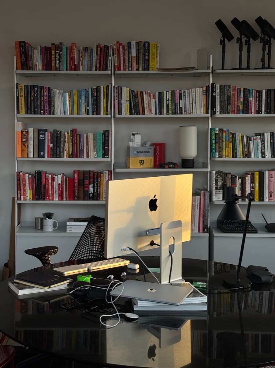 A desk with an iMac in front of a wall of bookshelves