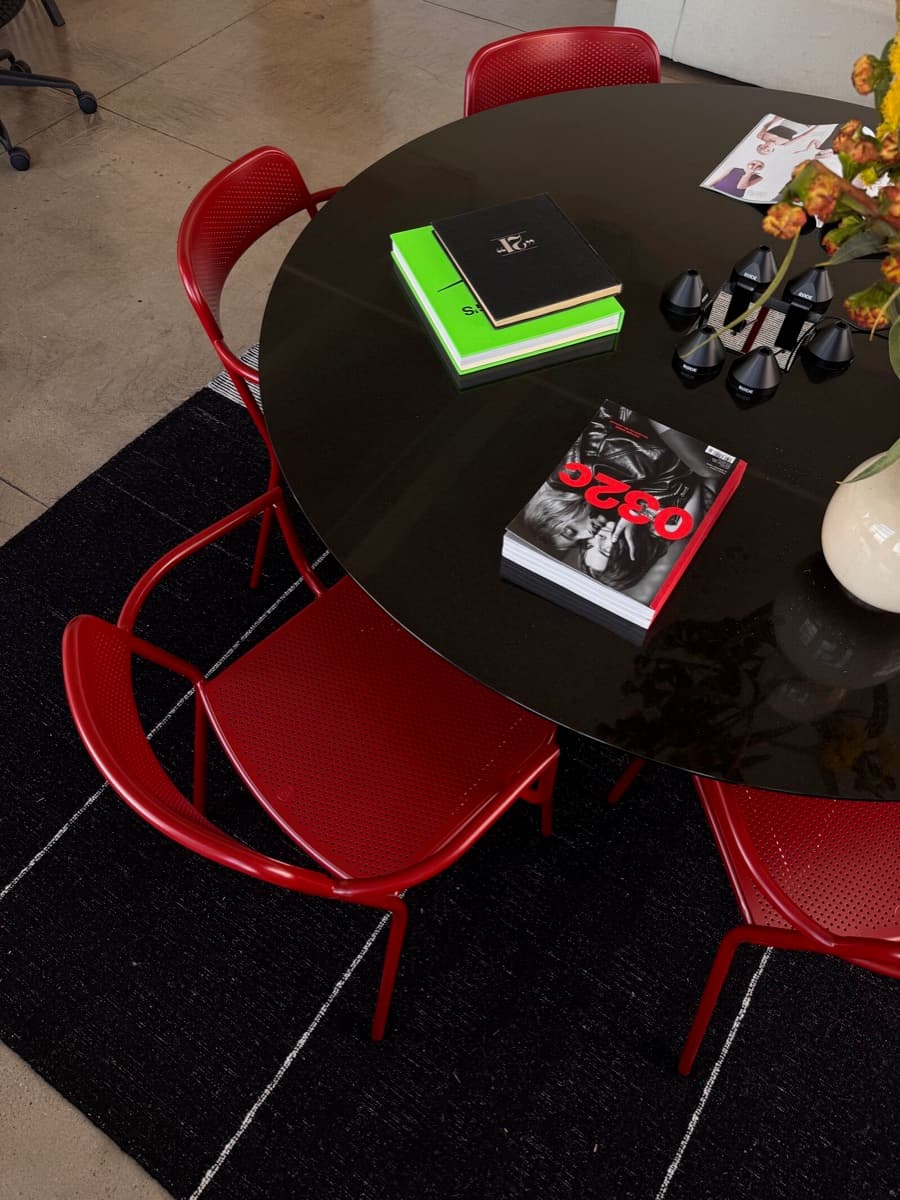 Red chairs around a black round table with books and microphones